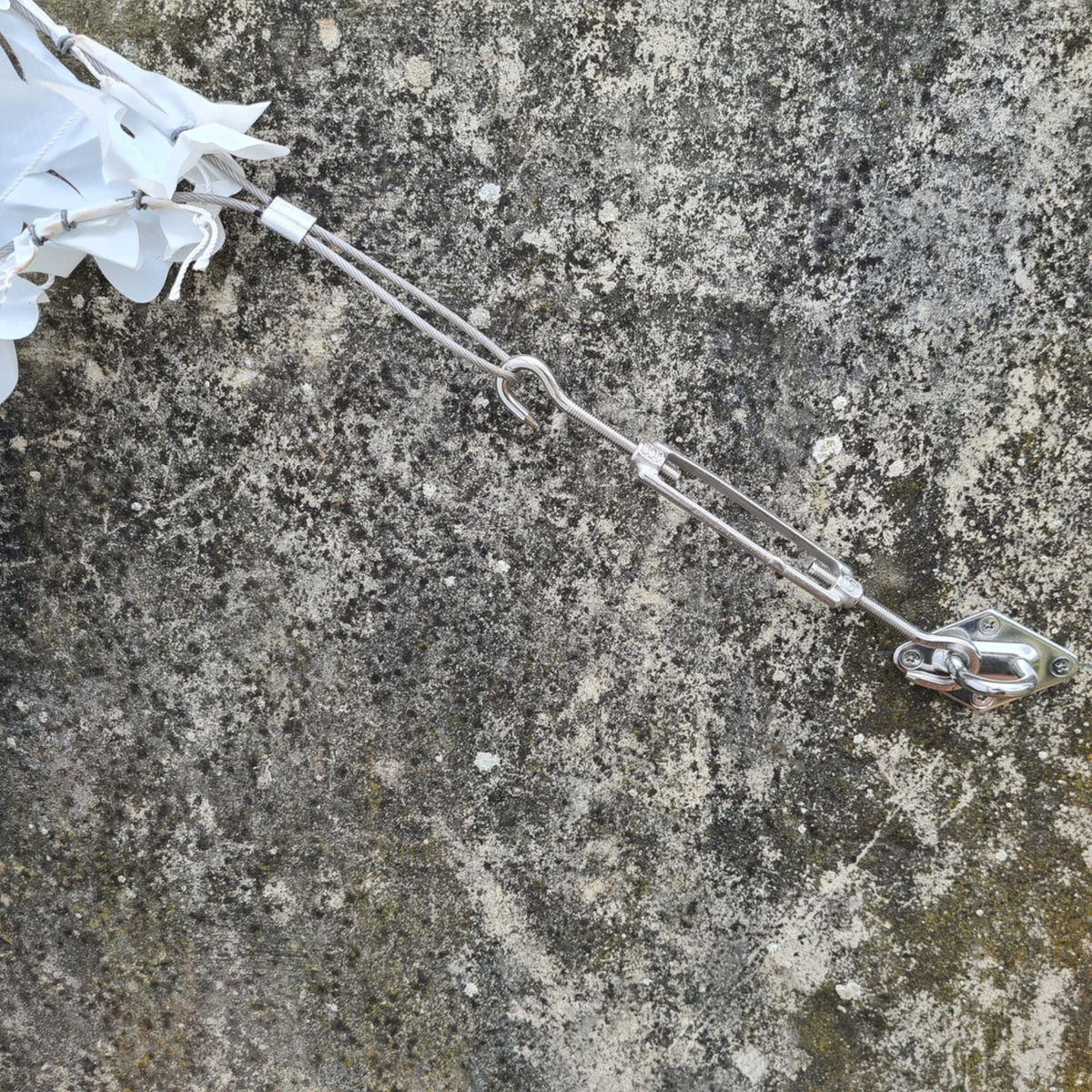 Tendeur et crochet de fixation sur un mur en pierre avec angle de filet de camouflage blanc